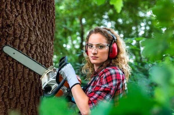 woman hand holding Chain Saw and cutting the tree
