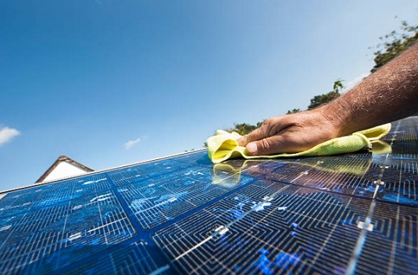 person clean the solar panel plate