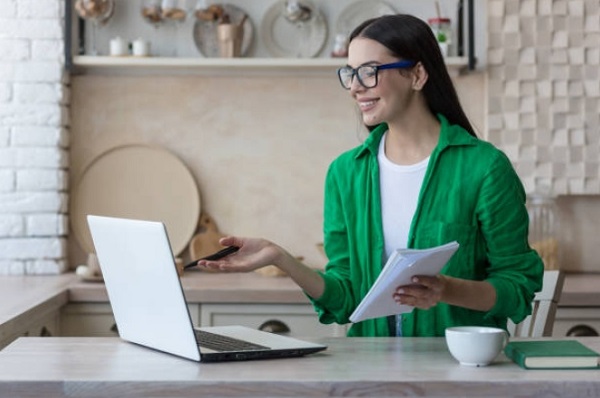 Hapyy woman look the laptop and hand holding pencil and notebook