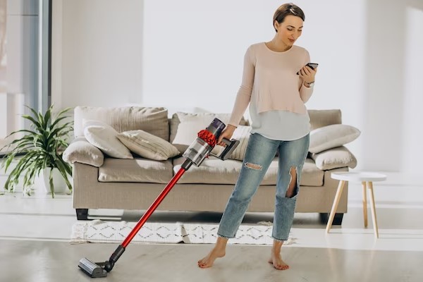 girl using phone and clean the floor with Cordless Vacuum Cleaner