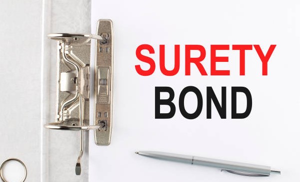 surety bond paper attached with clipboard and ball pen placed on it