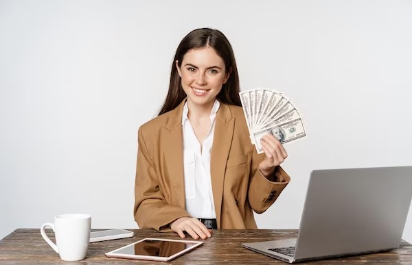Woman using laptop and hand holding money