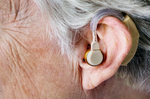 Hearing aid in the ear of an old woman