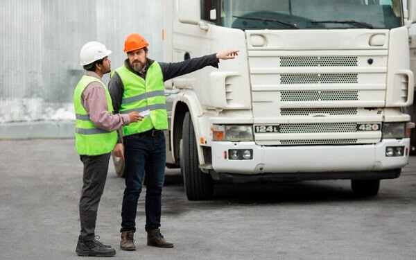 two workers standing beside the white truck