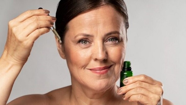 Old woman use cbd serum for skin care