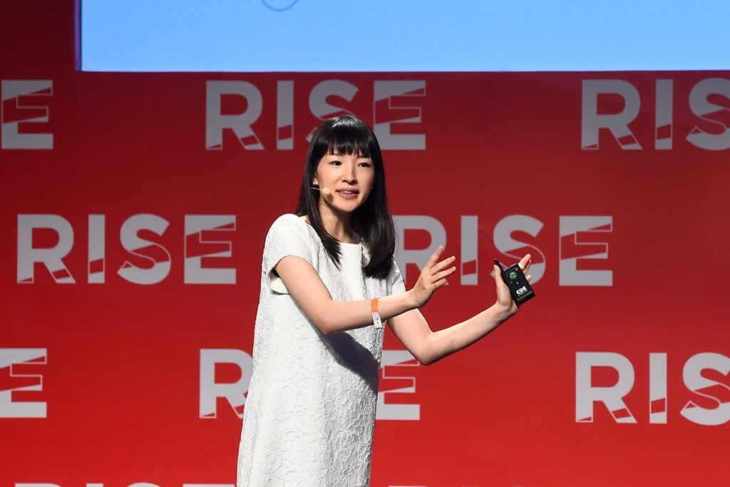 Marie Kondo on a stage and hand holding a mic